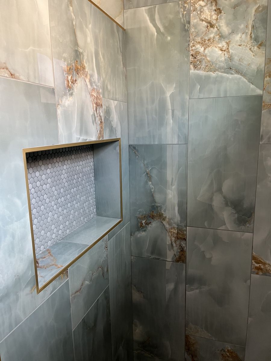 Onyx look tile shower with gold trimmed niche
