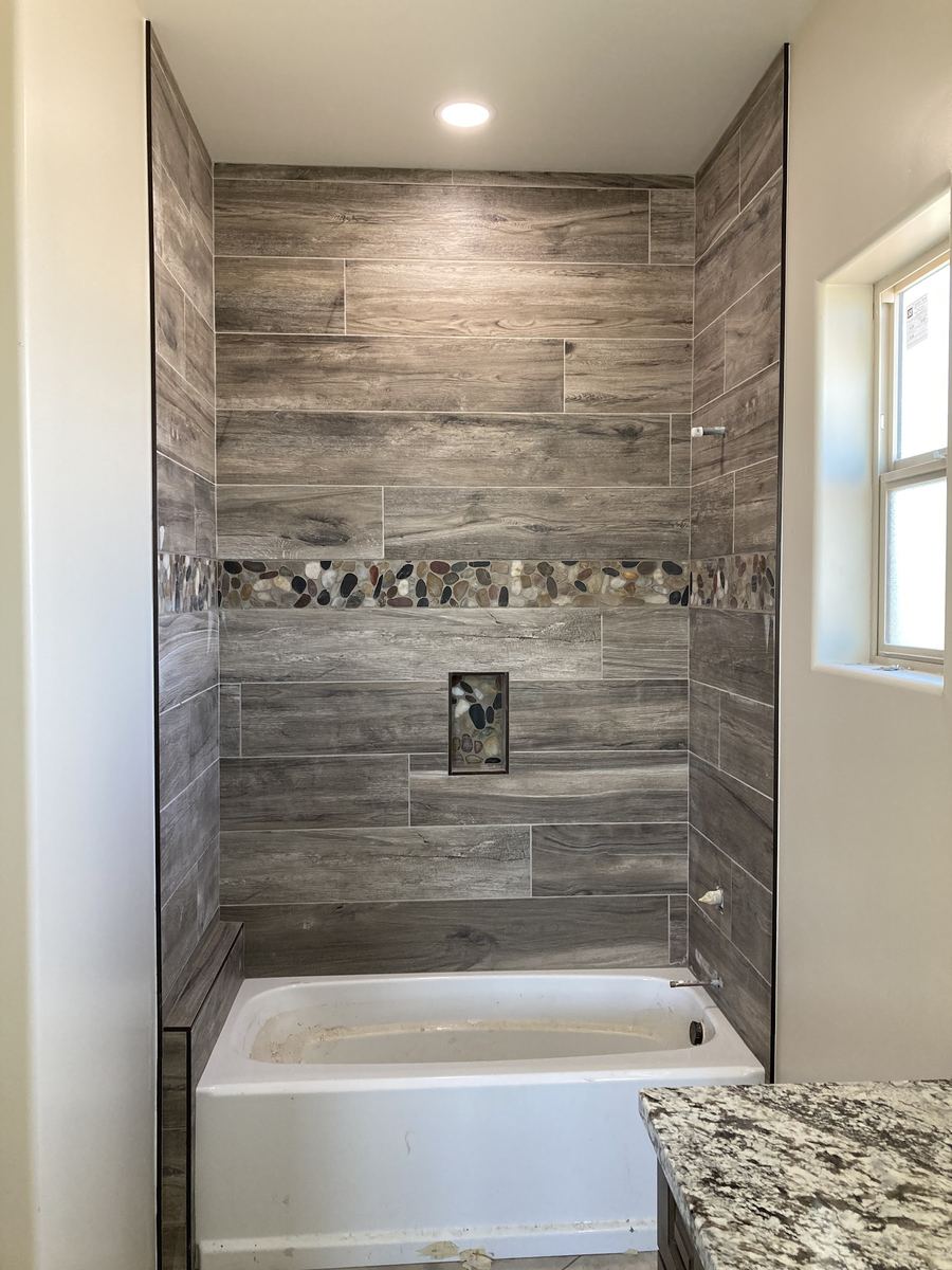 Wood look tile tub surround with pebble accent band